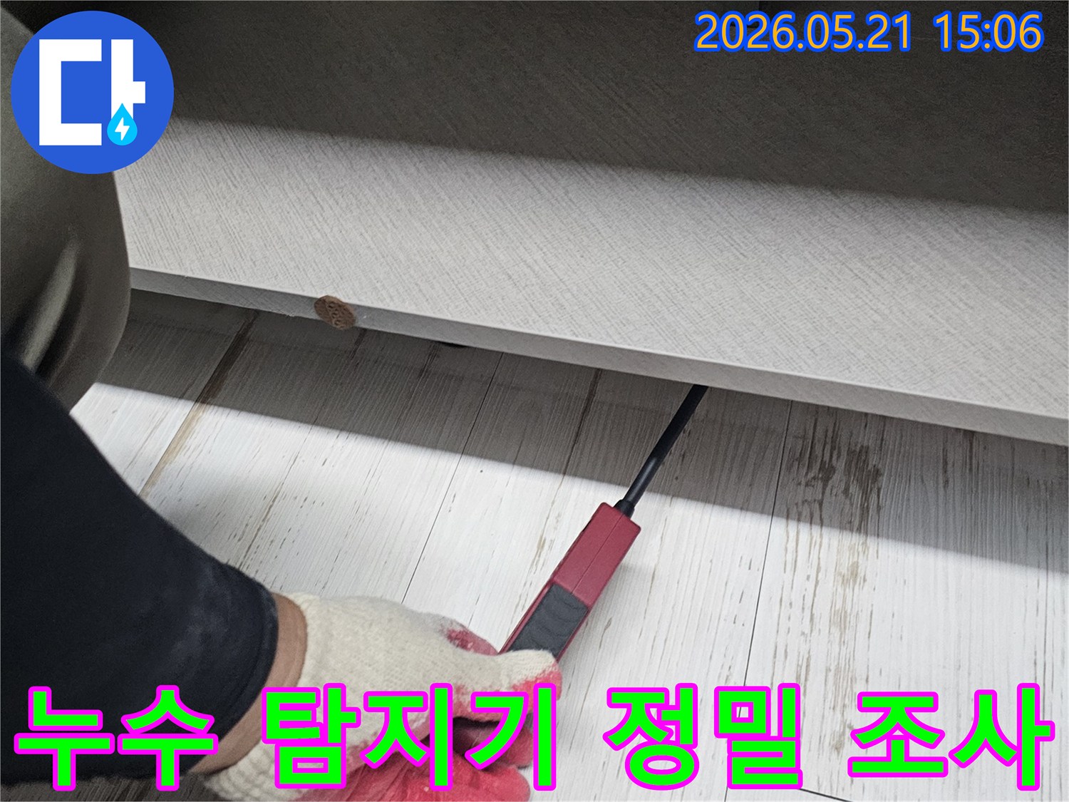 누수-전문가가-누수-탐지기를-이용해-바닥과-가구-틈새의-누수-지점을-정밀하게-조사하는-장면입니다