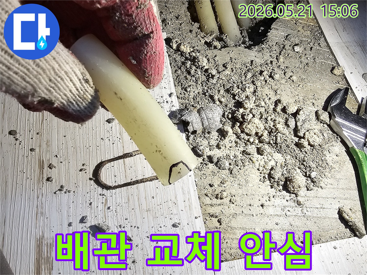 작업 장갑을 낀 손이 파손된 배관 조각을 들고-안심할 수 있는 교체 작업을 설명하는-현장 사진입니다