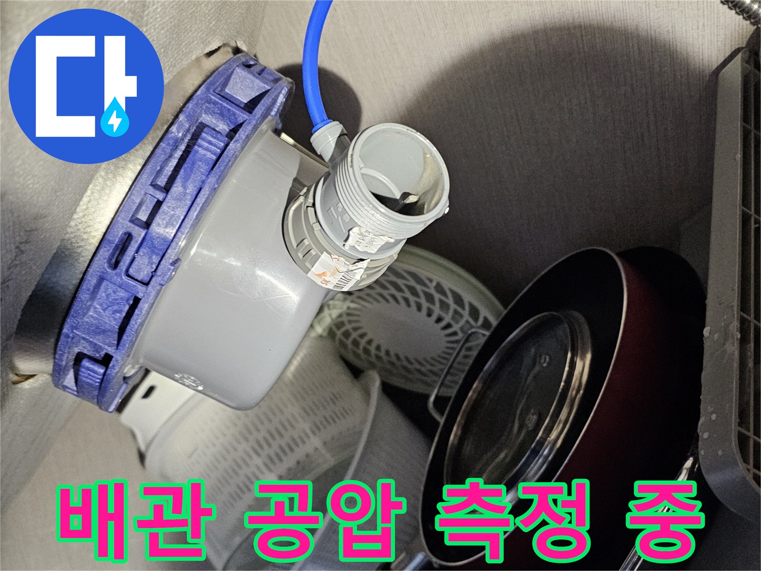 파란색 호스가 연결된 장비로 배관의 기밀성을 검사하는 장면