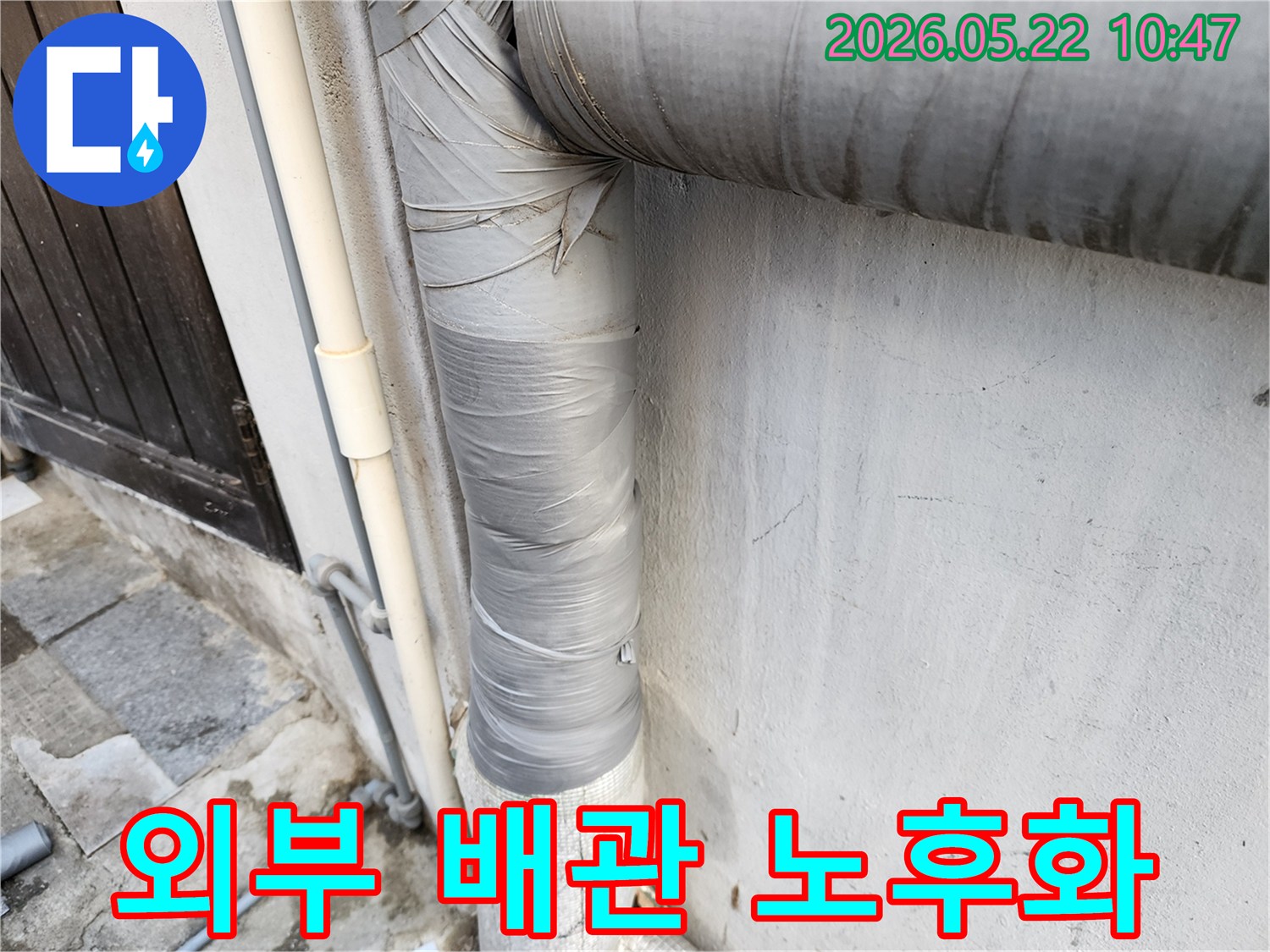 건물-외벽에-설치된-회색-배관의-보온재가-낡은-테이프로-감겨-있으며-전반적인-노후화가-진행된-모습입니다