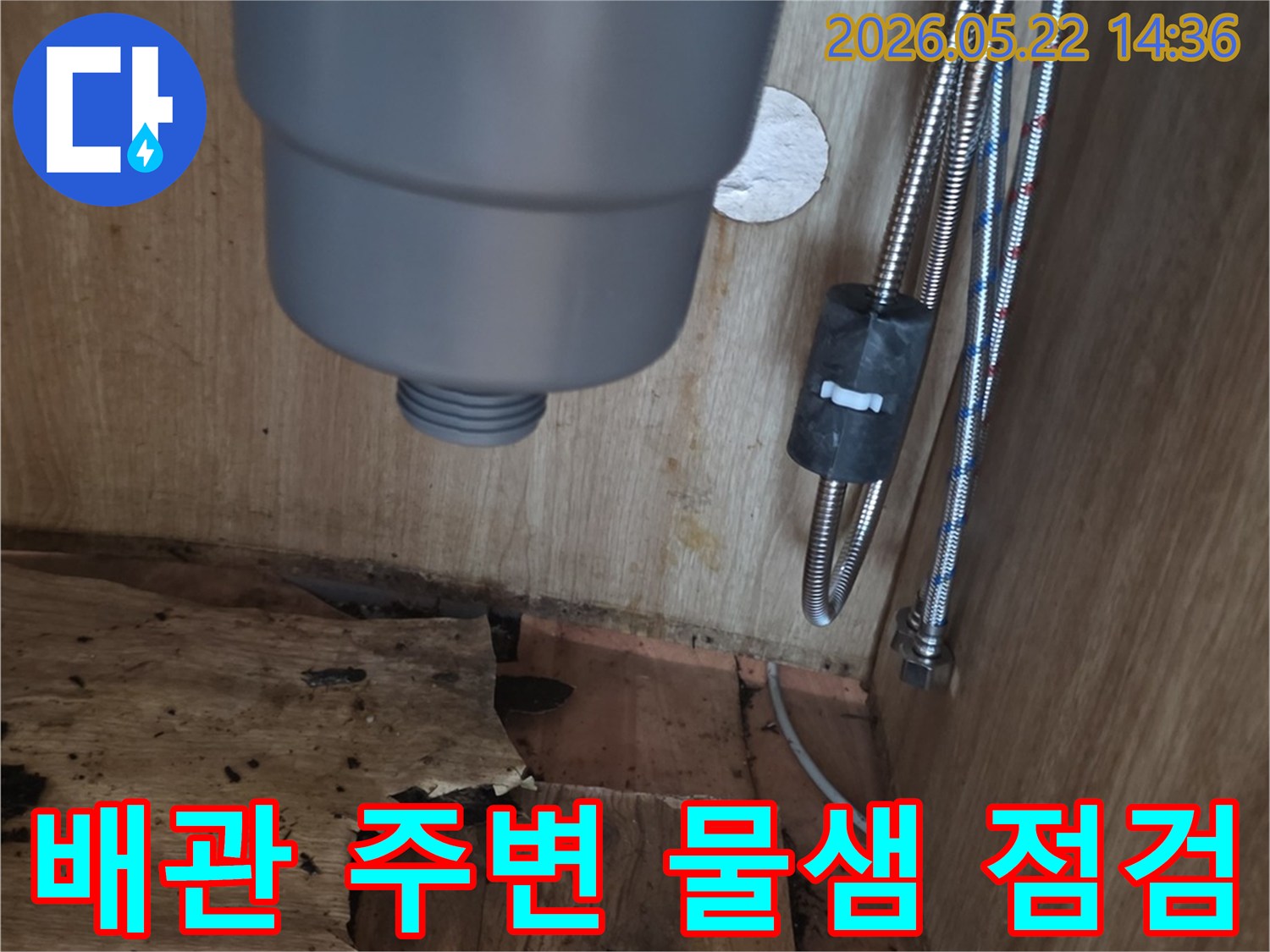 싱크대 하부장 내부의 물에 젖은 배관 주변과-손상된 목재-그리고 배관의 모습을-전문가가 면밀히 점검하는 현장 사진