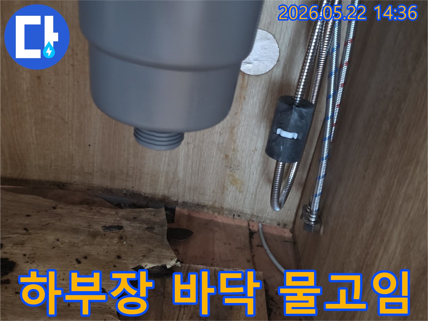 싱크대 하부장 바닥에 고인 물과-물에 젖어 손상된 목재-그리고 배관의 모습을 보여주는 누수 현장