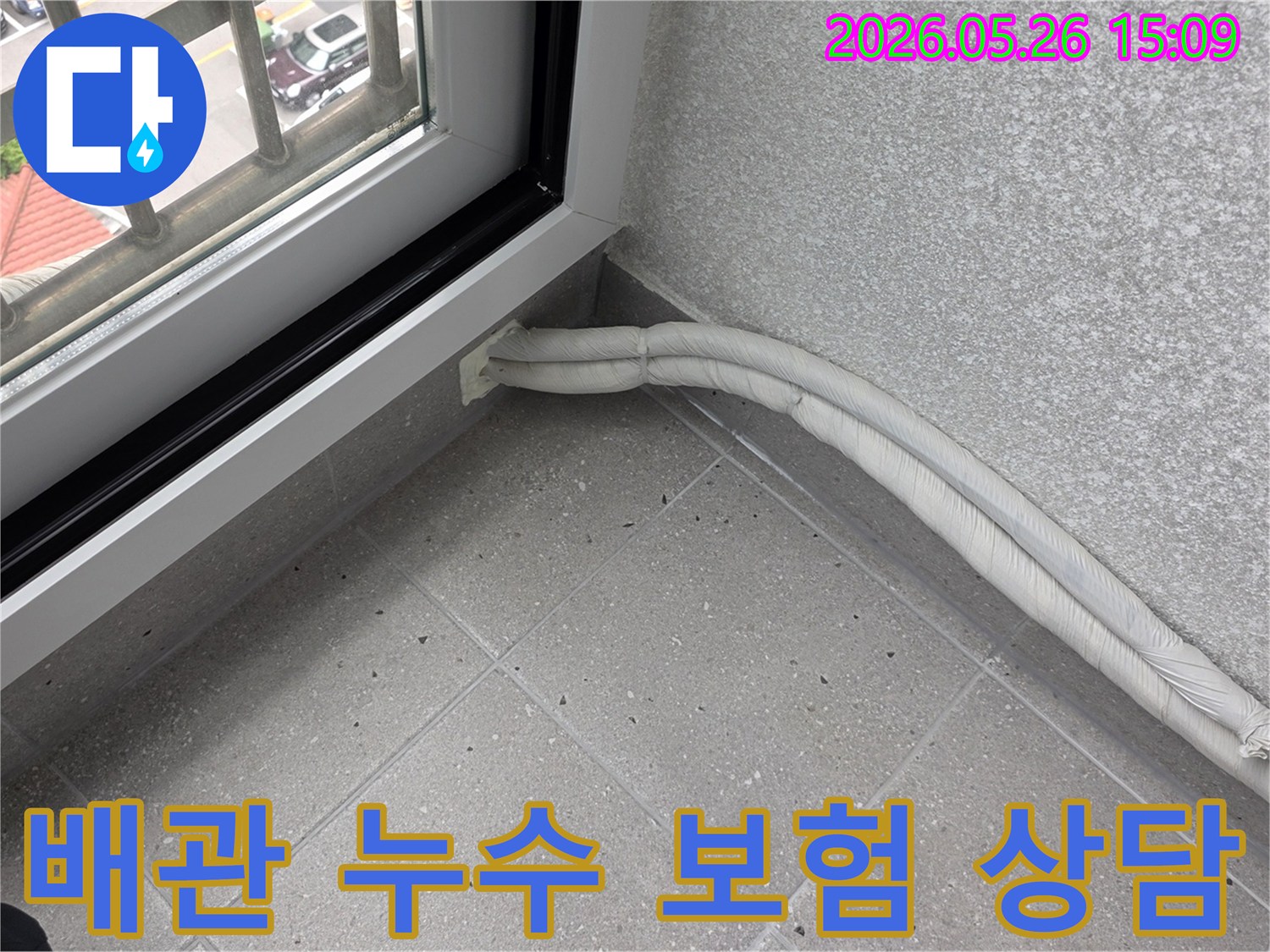 창문 옆 바닥에-보온재로 감싸진-두 개의 배관이-설치된 모습으로-누수 보험 처리에-대한 상담을-진행합니다.