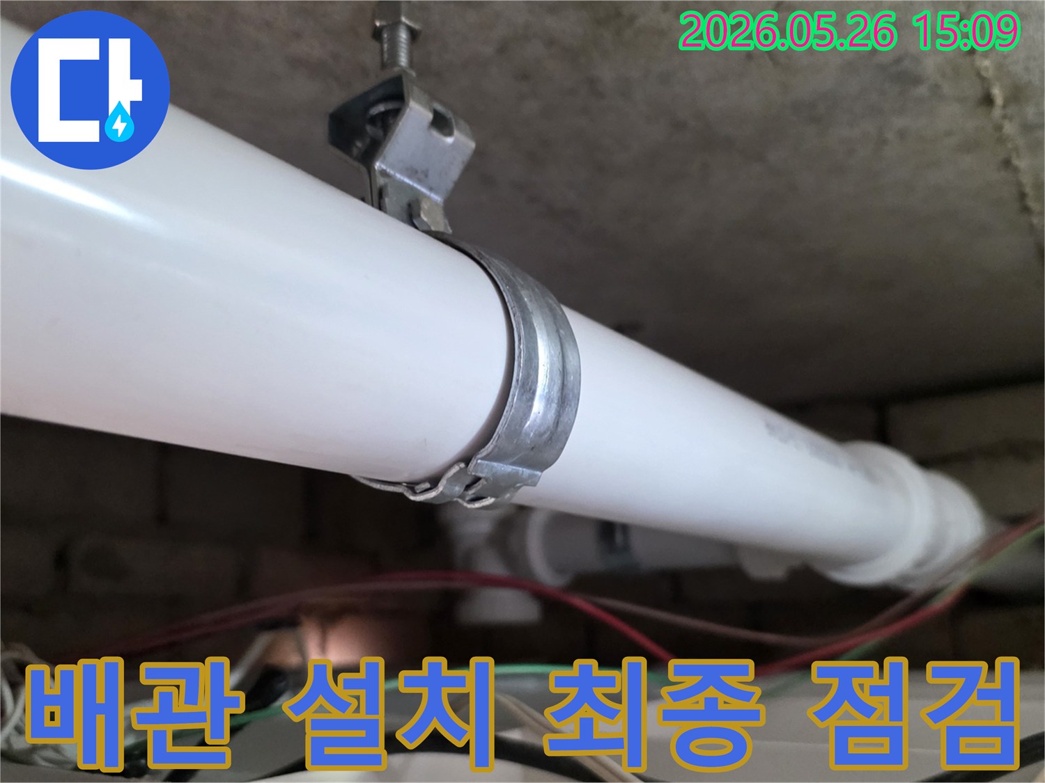 천장에 설치된 PVC 배관과-이를 지지하는 금속 클램프의 모습-배관 설치 완료 후 최종 점검 단계