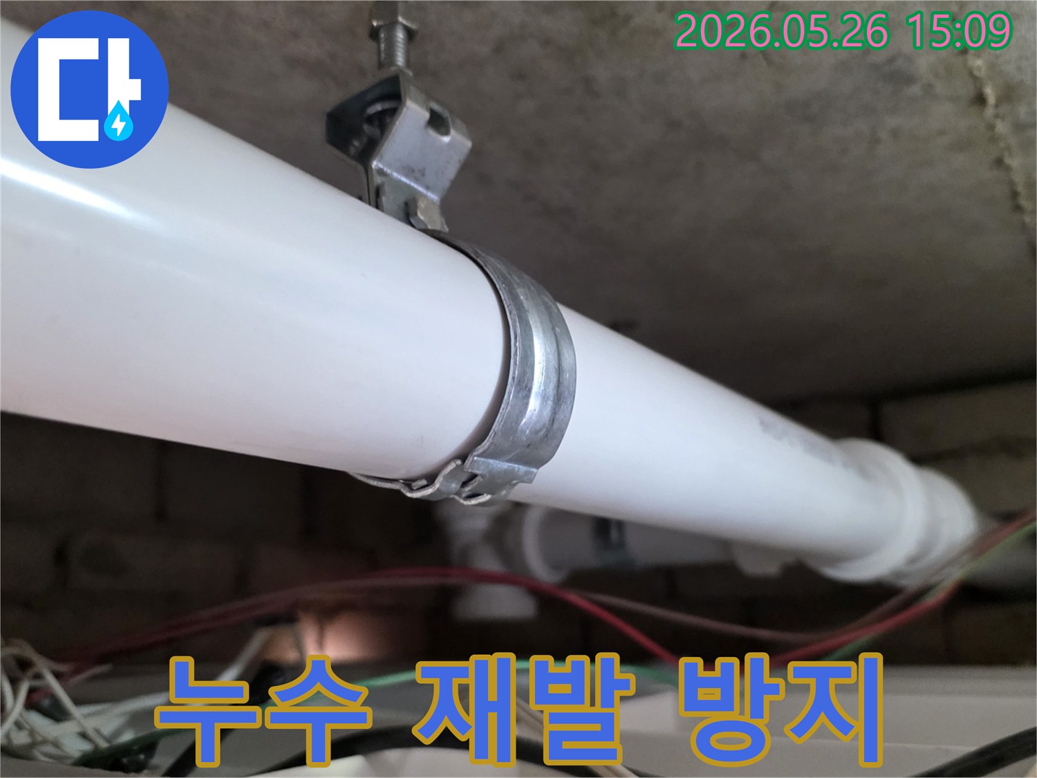 천장에 설치된 PVC 배관을-견고하게 고정하는 금속 클램프-누수 재발을 막기 위한 핵심적인 작업