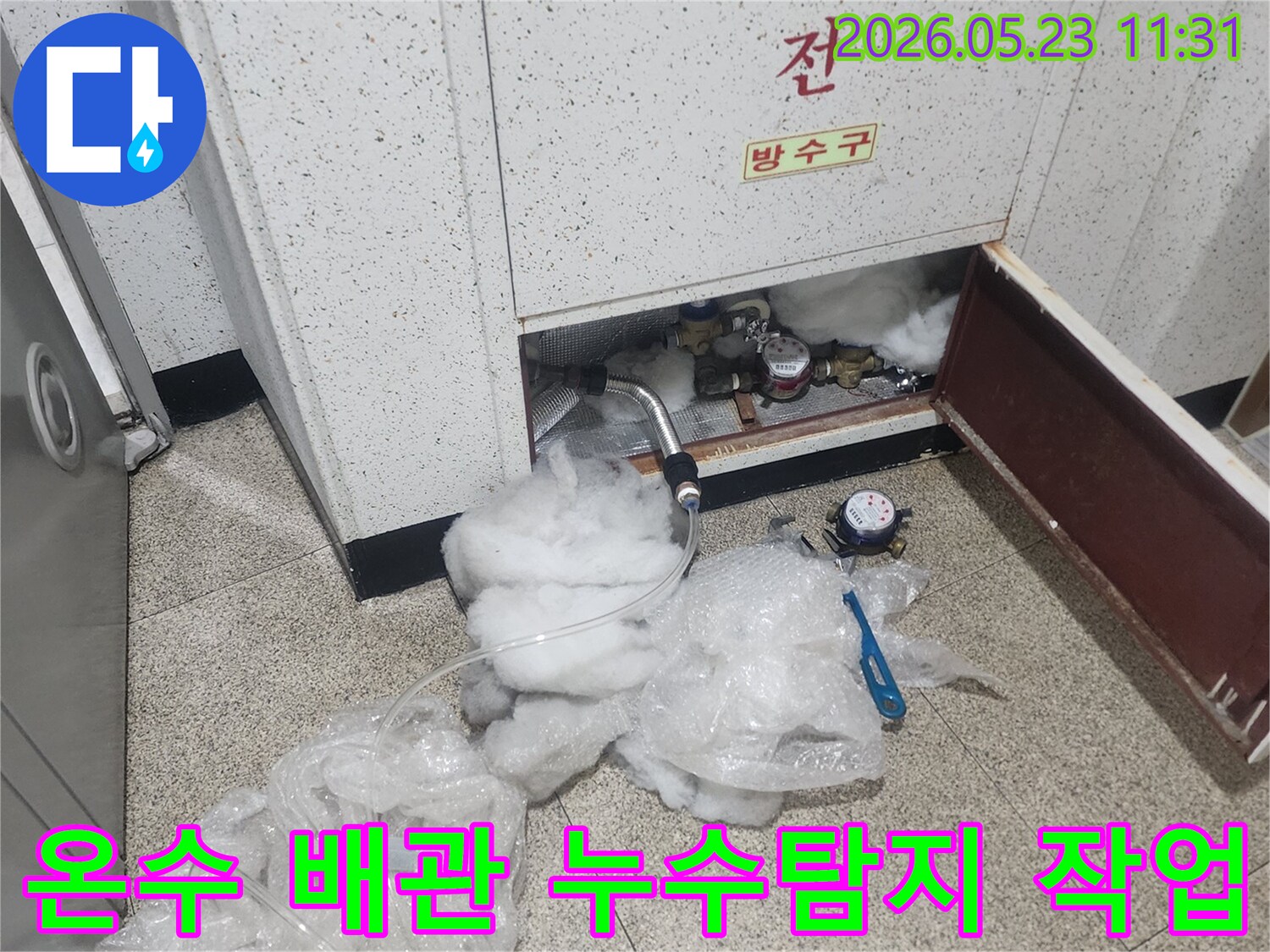 온수 배관의 누수 지점을 찾기 위해-압력 게이지와 탐지 장비를 설치하여-정밀하게 탐지하는 모습입니다.