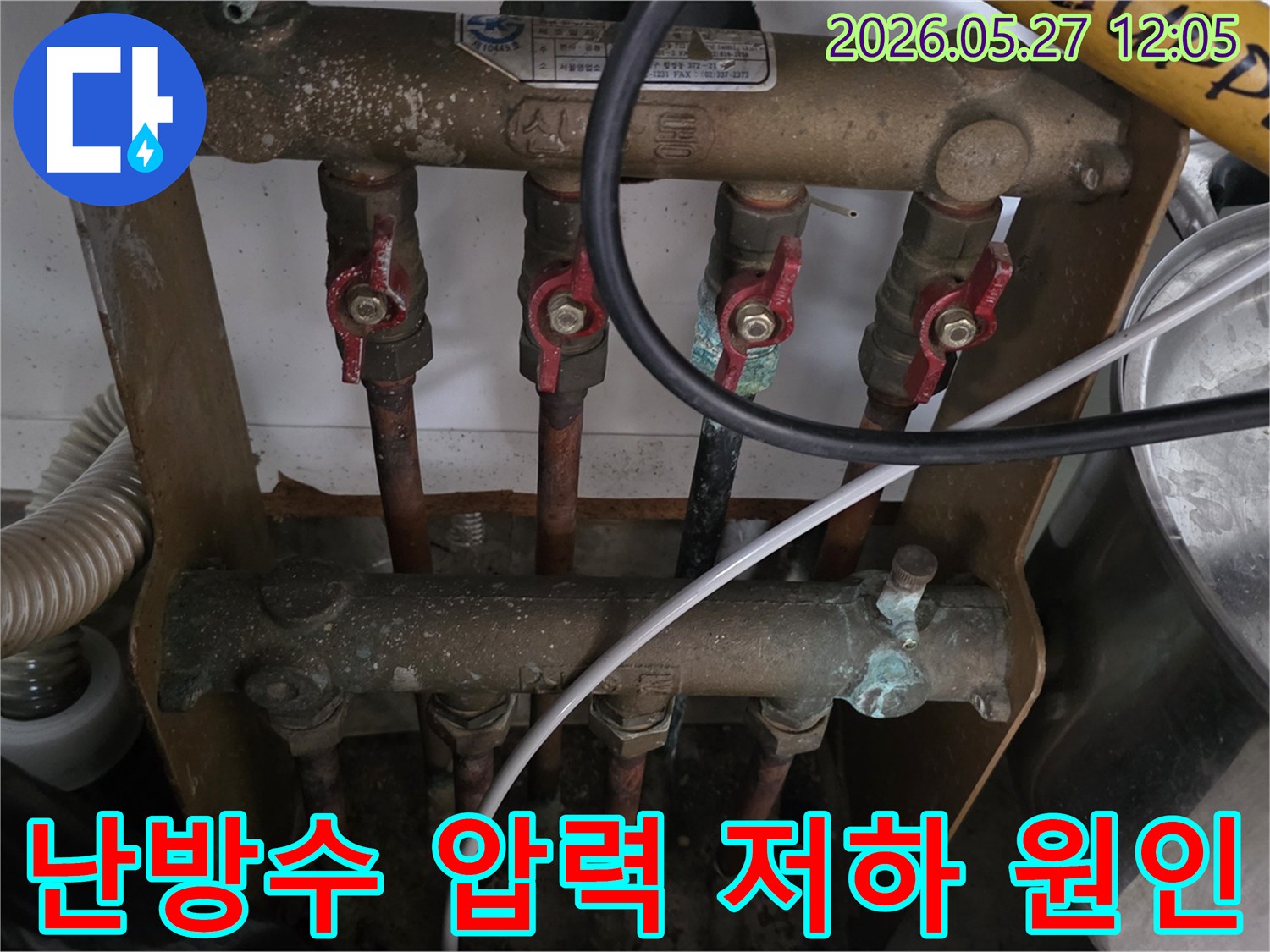 오래된 아파트의 보일러 분배기에서-난방수 압력 저하의 원인을 찾기 위해-전문가가 배관과 밸브 상태를-점검하고 있는 모습입니다