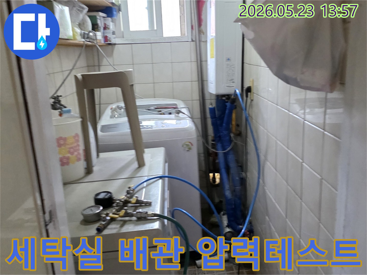 묵동 빌라 세탁실에서 누수 원인을 찾기 위해 배관에 압력 테스트 장비를 연결하여 확인하는 모습입니다-정확한 진단을 위한 첫 단계입니다