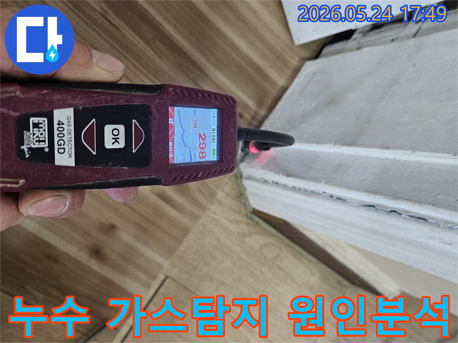 누수 엔지니어가 가스 탐지기를 사용하여 벽면과 바닥 경계에서 누수 반응을 정밀하게 확인하고 있습니다.