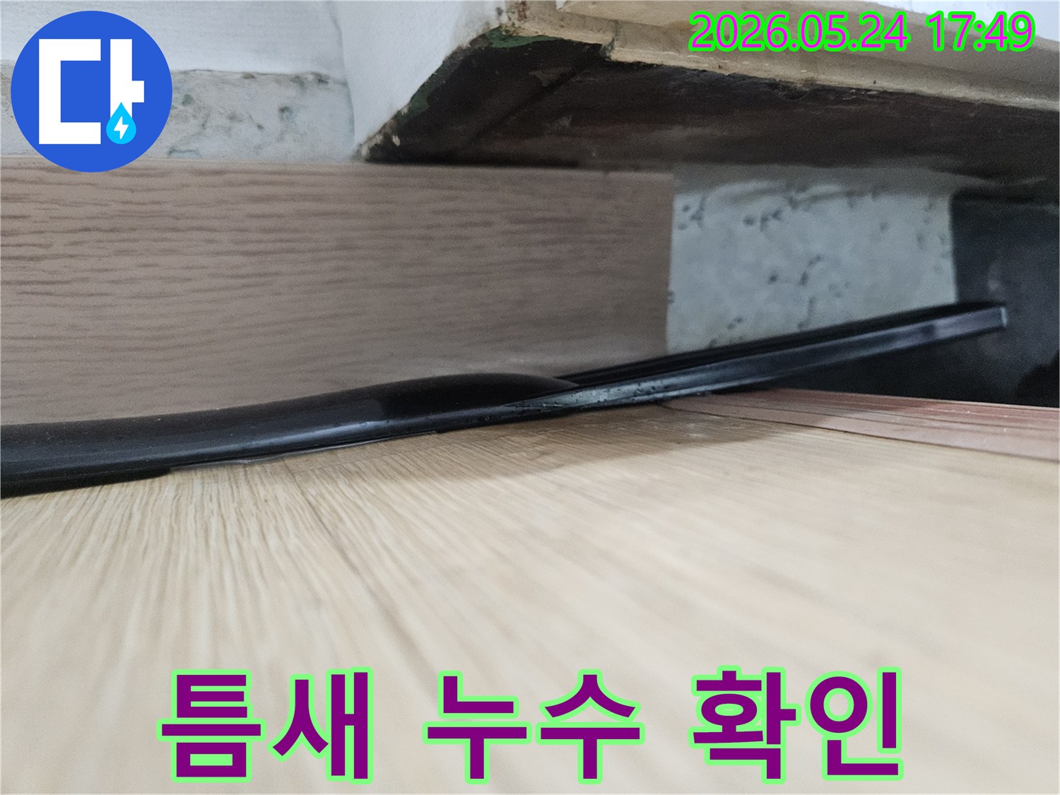 마루 틈새로-스며든 물이-아래쪽 구조물에-습기와-변색을 유발한-누수 현장 사진