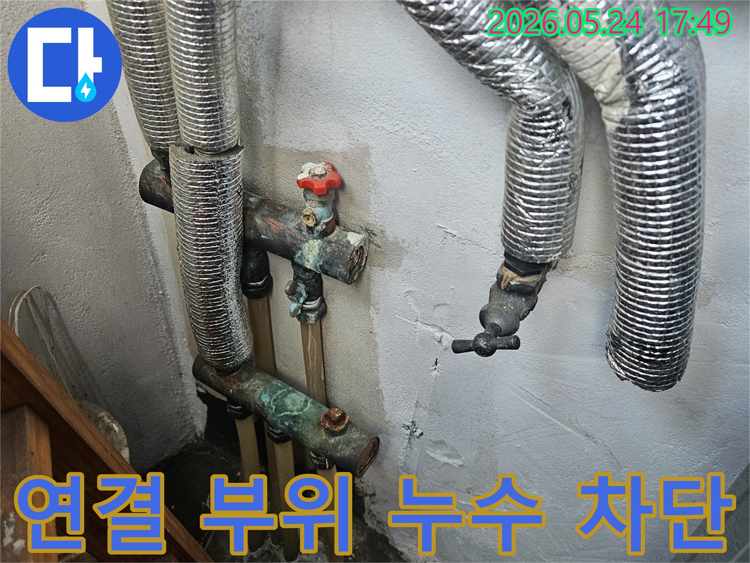 배관 연결 부위에서 발생한 누수-부식된 연결 부위와 젖은 벽면이 보입니다