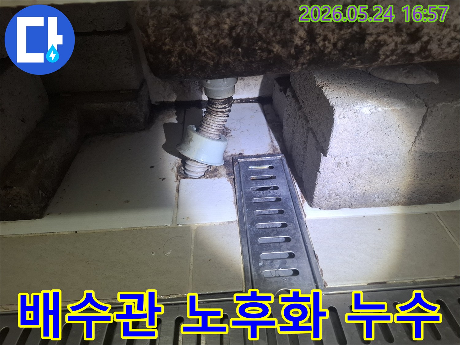 이 이미지는 광명 아파트 배수관의 심각한 노후화와 주변의 누수 흔적을 보여줍니다-전문가가 누수 해결을 위해 현장을 점검하고 있습니다.