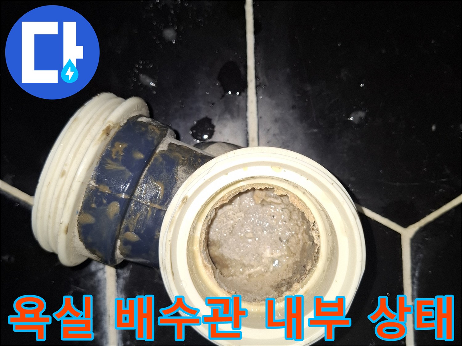 검은색 타일 사이의 노출된 배수관 연결 부위 모습