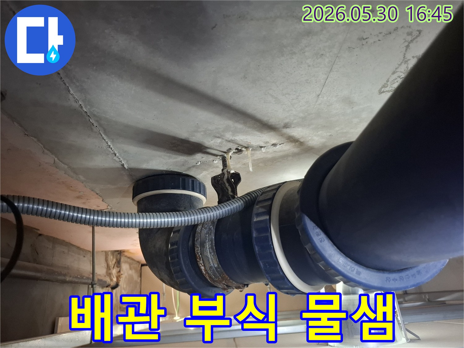 콘크리트 천장 아래-설치된 배관의-부식된 이음새에서-물이 새어 나와-천장에 물방울을-만드는 모습입니다.
