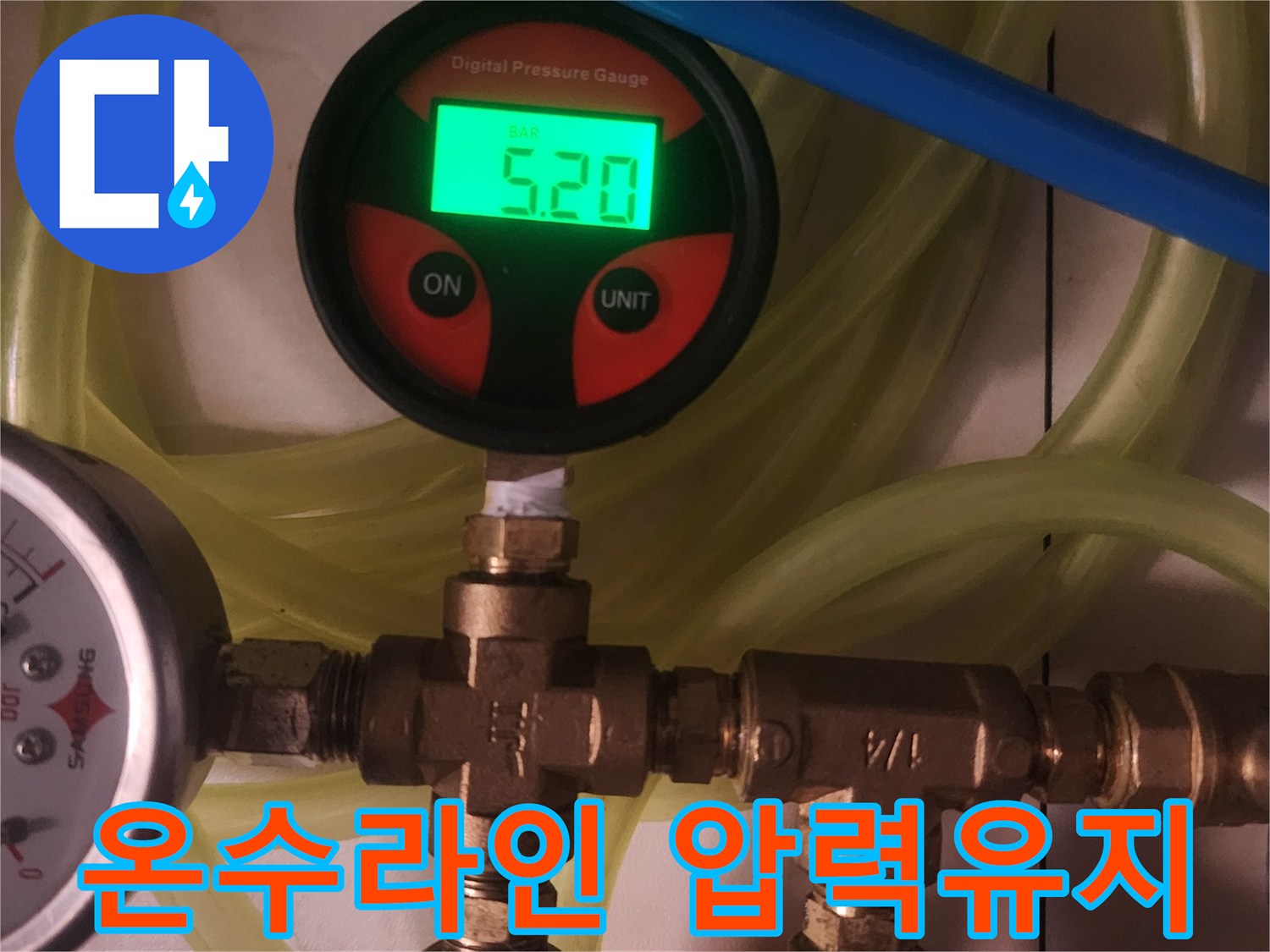 이 사진은 주거 시설의 온수 배관에서-누수 발생 여부를 확인하기 위해-디지털 압력 측정 장비를 사용하여-배관의 압력 유지 상태를 면밀히 검토하는 모습입니다.