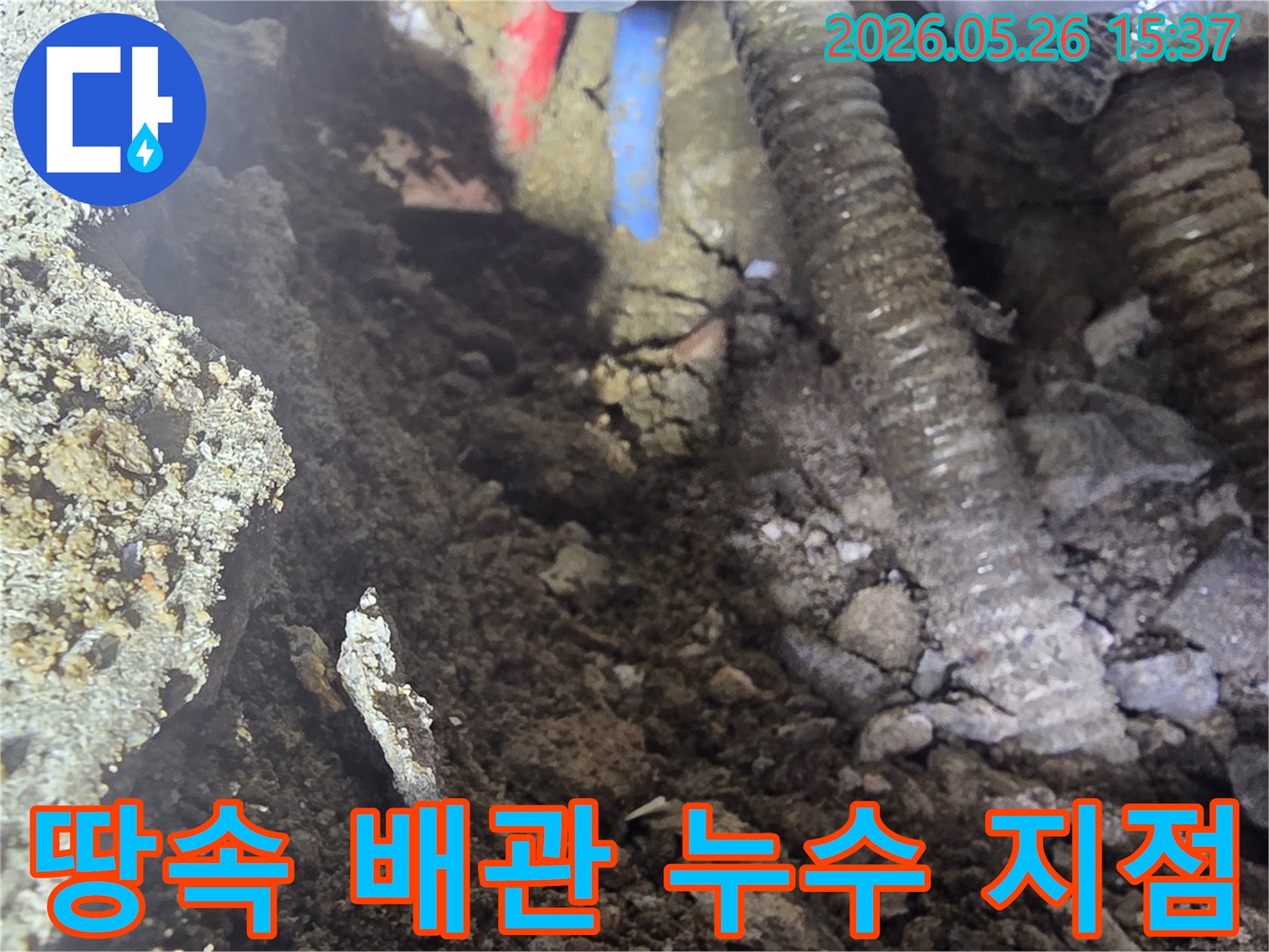 이 이미지는 땅속에 묻힌 수도-온수 배관에서 발생한 누수 지점을 정확히 찾아내어 공사하는 현장을 보여줍니다.