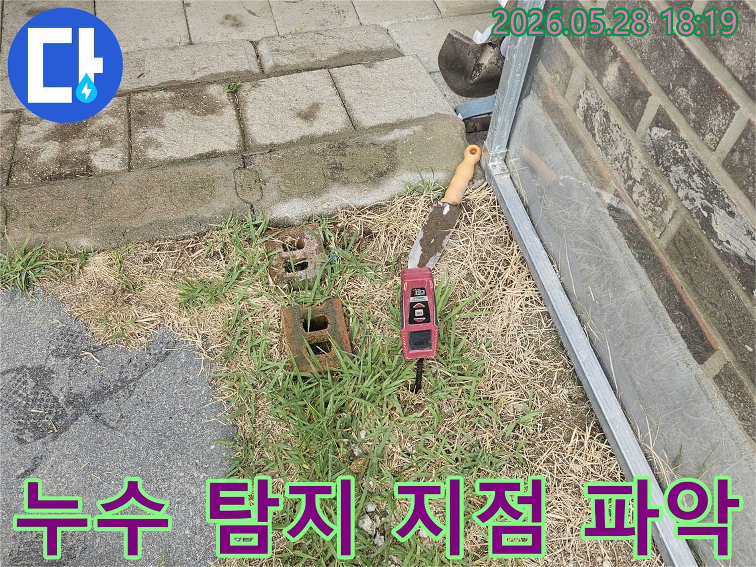 누수 탐지 현장에서-정확한 누수 지점을 파악하기 위해-삽과 정밀 수평계가 사용되고 있는 모습입니다