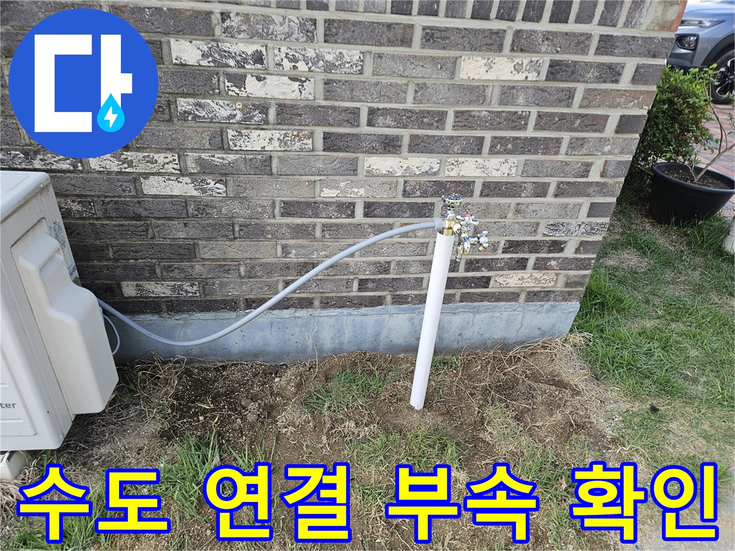 벽돌 벽면에 설치된 은색 금속 부속과 흰색 파이프의 모습
