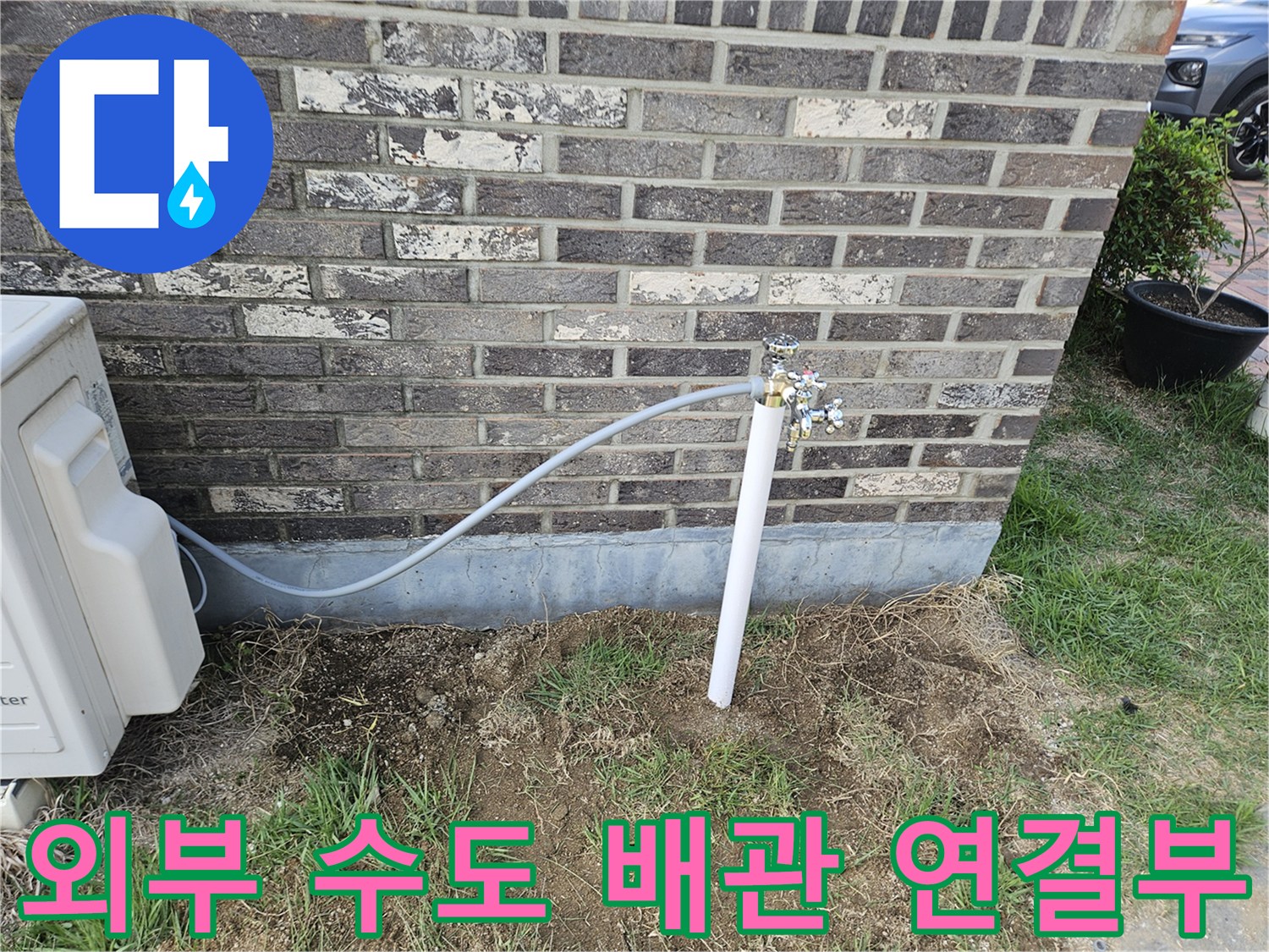 벽돌 외벽에 설치된 외부 수도꼭지와 연결 호스 모습