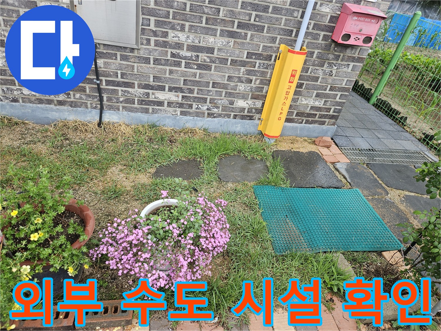 주택 외벽 근처에 설치된 야외 수도 및 소화전 주변 모습입니다.