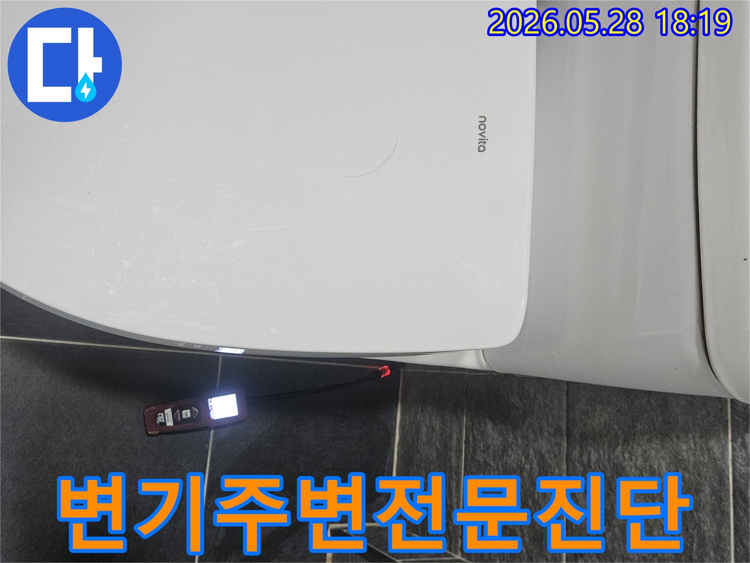 화장실 변기 옆-어두운 바닥 타일 위에서-누수 탐지기가-빨간색으로-누수 지점을 표시하고 있습니다.