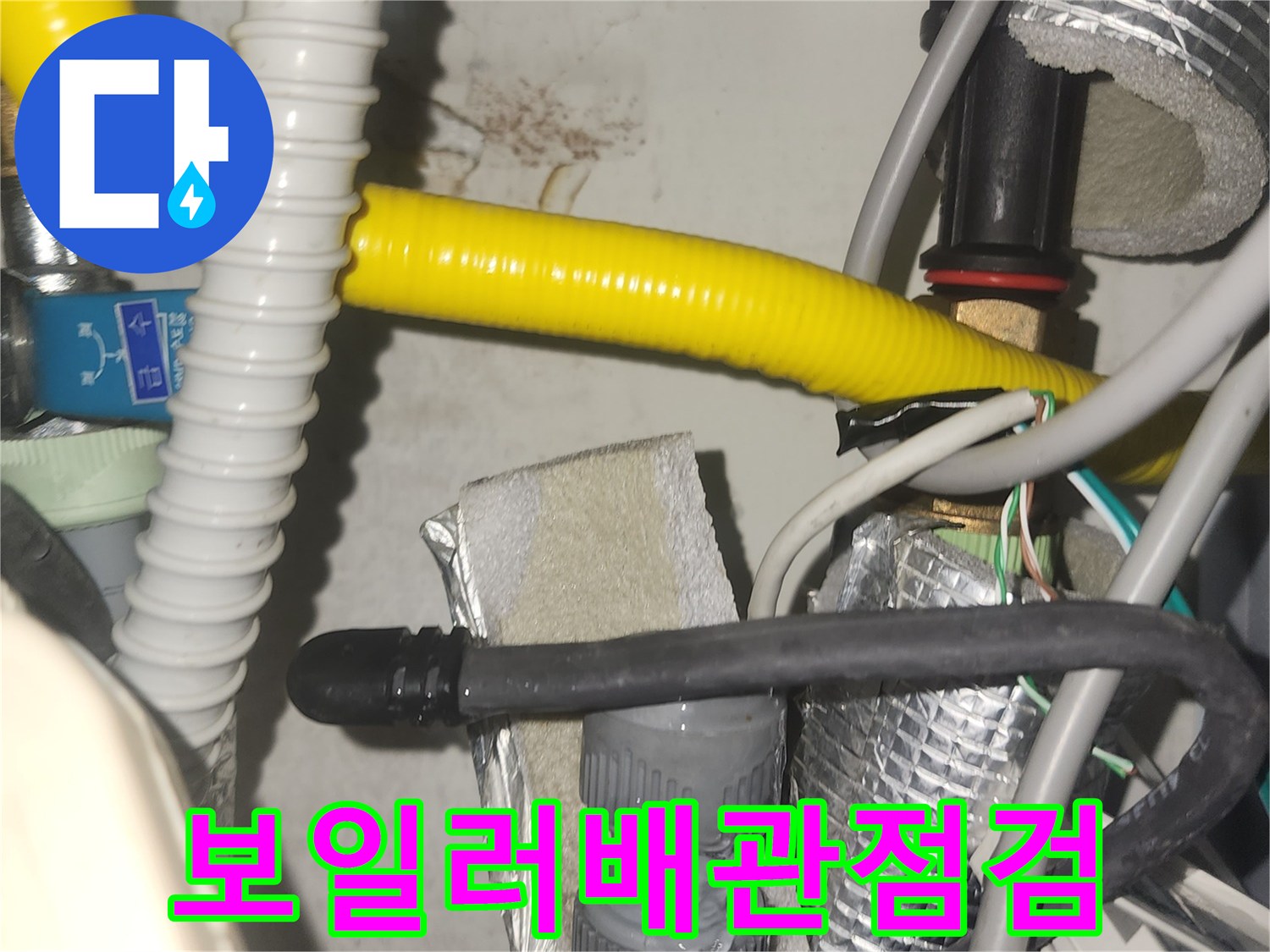 누수 발생 지점을 찾기 위해-배관의 밀집된 부분을 면밀히 살피는 모습입니다-벽면의 얼룩이 누수의 증거를 제시합니다