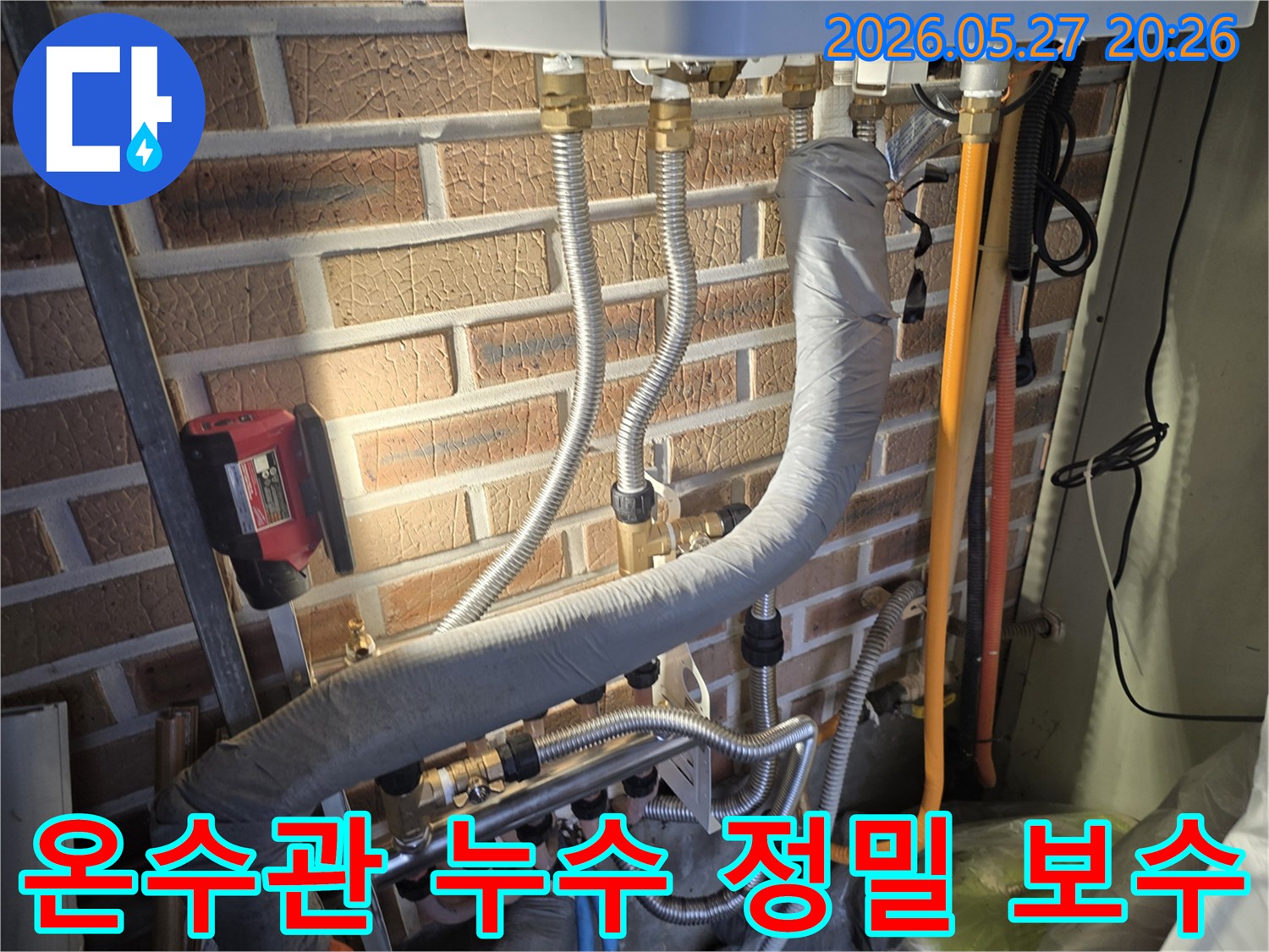 이 이미지는 벽돌 벽에 설치된 온수관 배관과-다양한 연결 부위 그리고 단열재를 보여주며 누수 점검의 중요성을 강조합니다.
