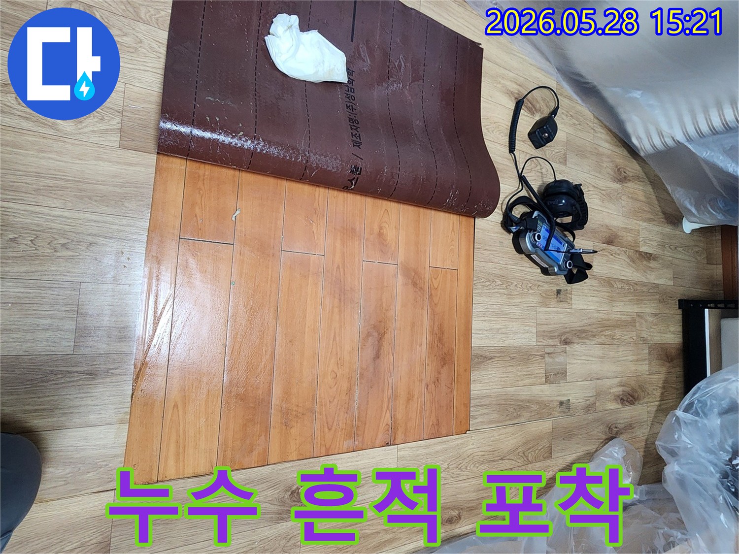 누수-탐지-전문가가-인천-남촌동-누수-현장에서-손상된-마루와-함께-누수-장비를-활용하여-흔적을-포착하는-장면입니다