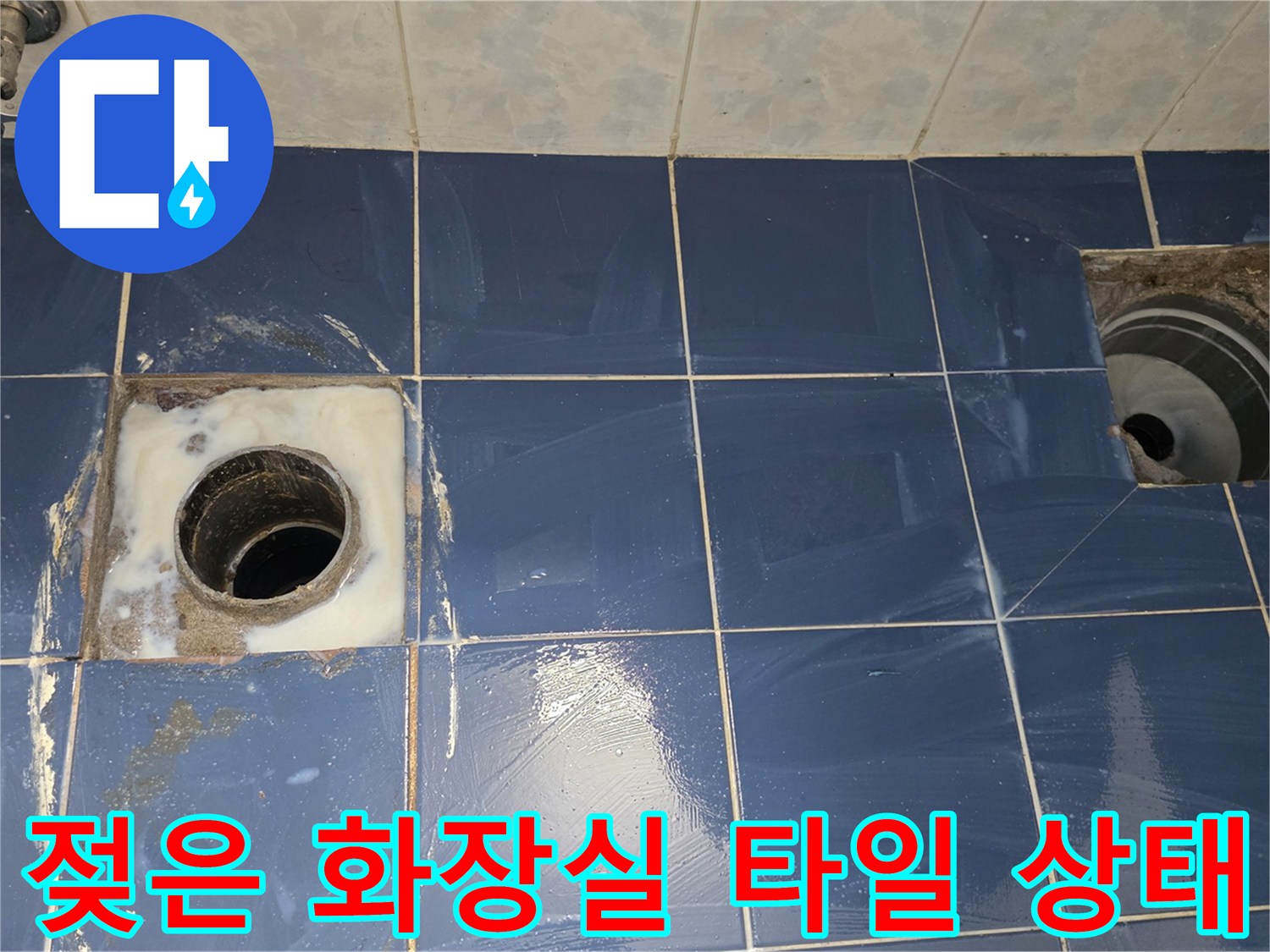 배수구 주변으로 물기가 스며든 화장실 바닥 타일 사진