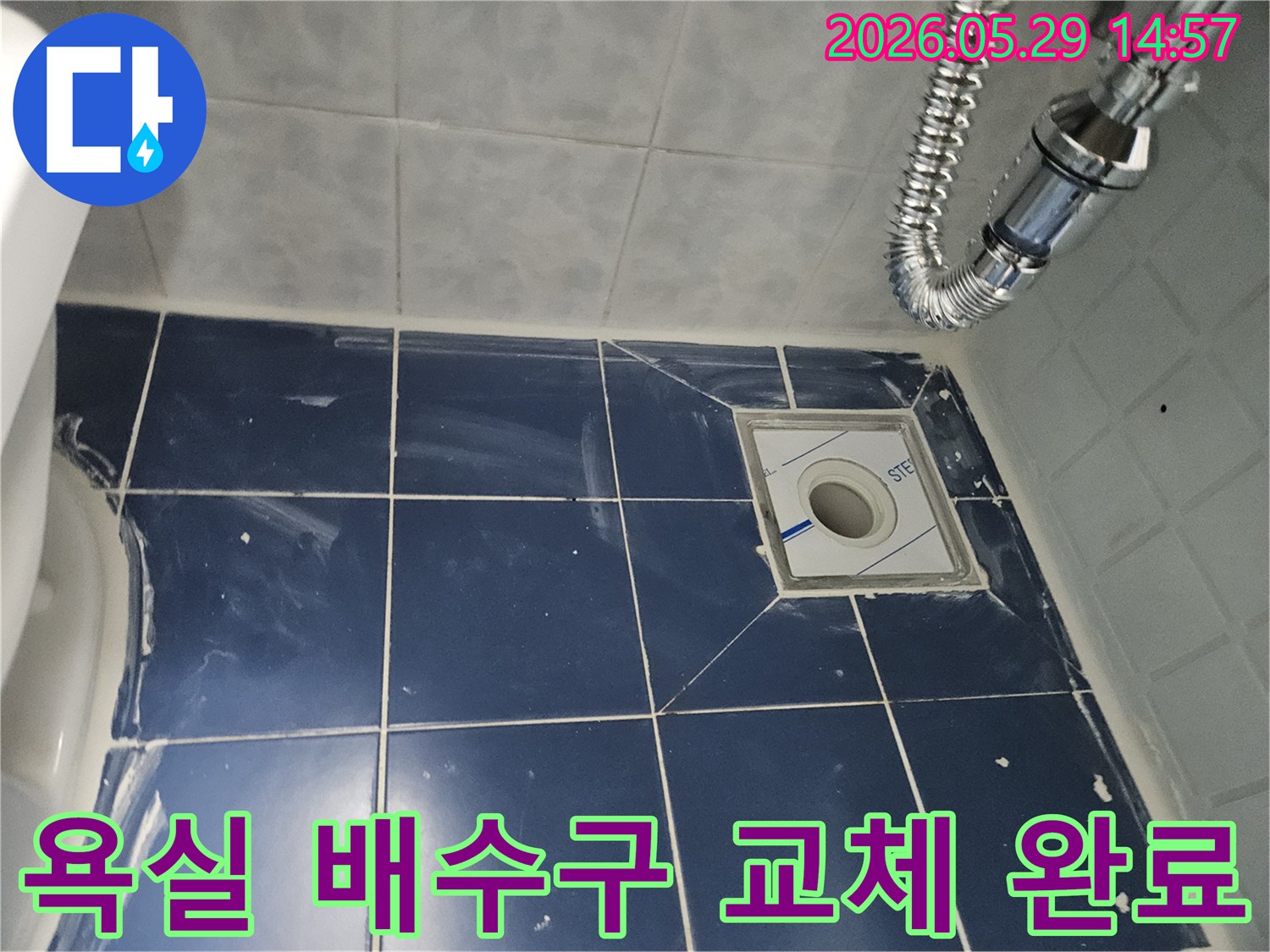 욕실 바닥의-새로운 배수구와-주변의 깨끗한 타일-그리고 연결된-유연한 배수관이-보이는-누수-수리-현장-사진입니다