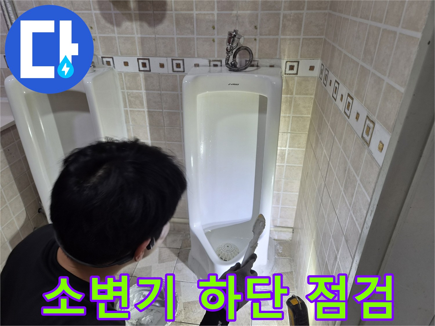 소변기 아래쪽 배관 연결 부위를 세밀하게 관찰하는 엔지니어