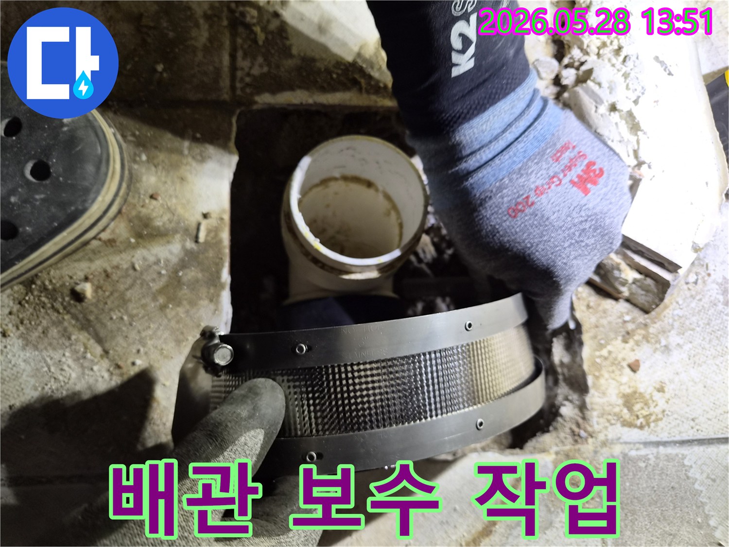 작업자가 안전 장갑을 착용하고-파손된 배관 연결 부위를 수리하기 위해-보강 밴드를 설치하는 모습입니다
