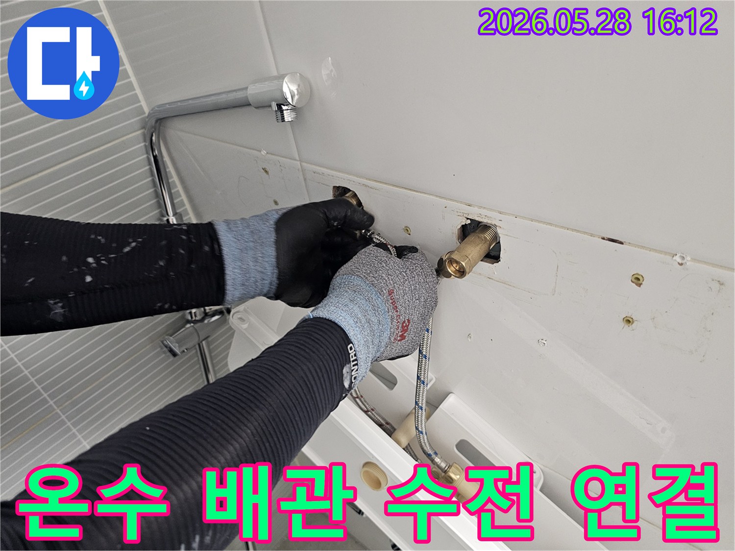 장갑을 낀 손으로-화장실 벽 속의-수도 배관을 조심스럽게 연결하고 있습니다.