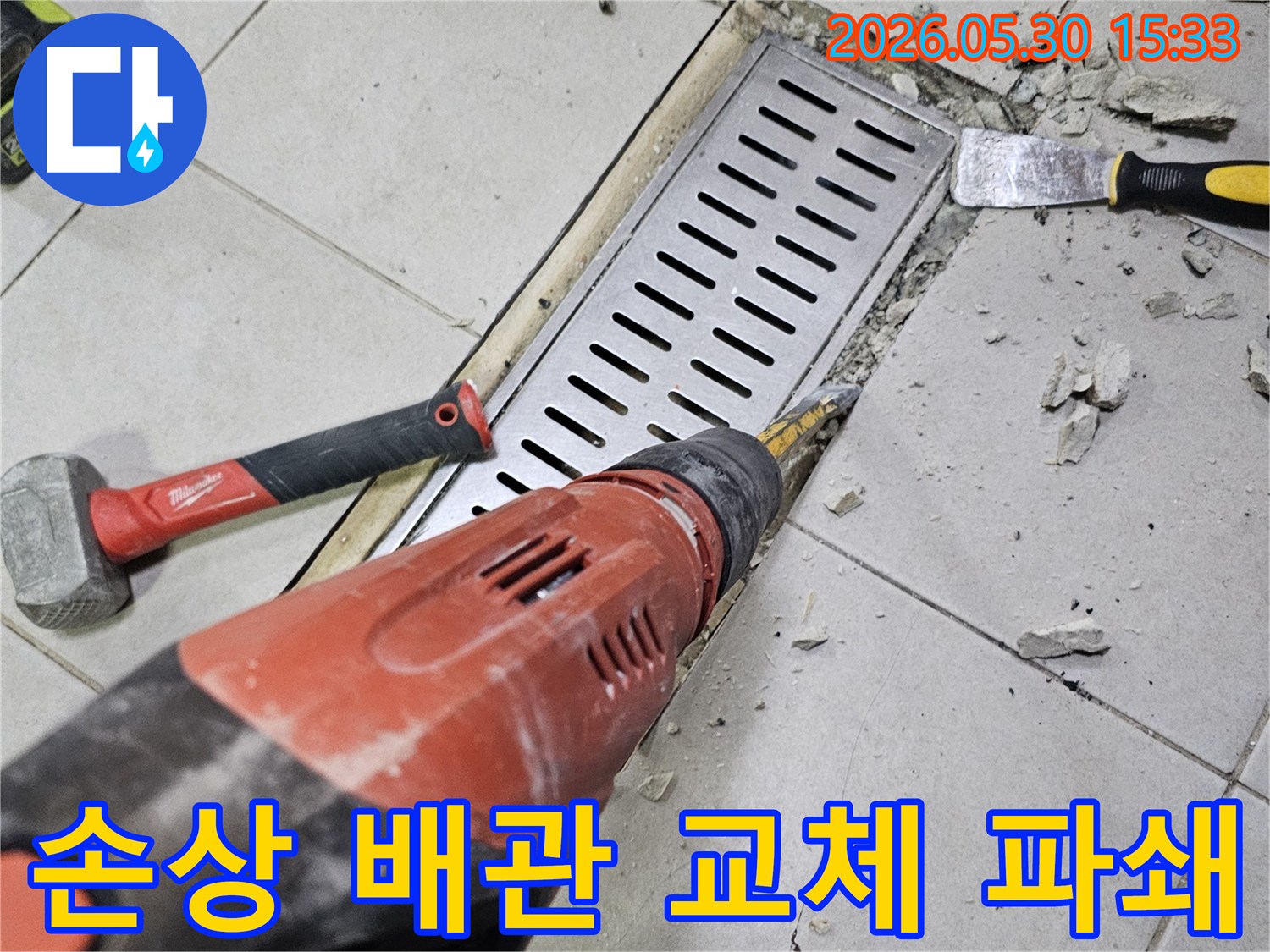 손상된 배관을 교체하기 위해-바닥 타일과 콘크리트를-파쇄하는 누수 공사 현장