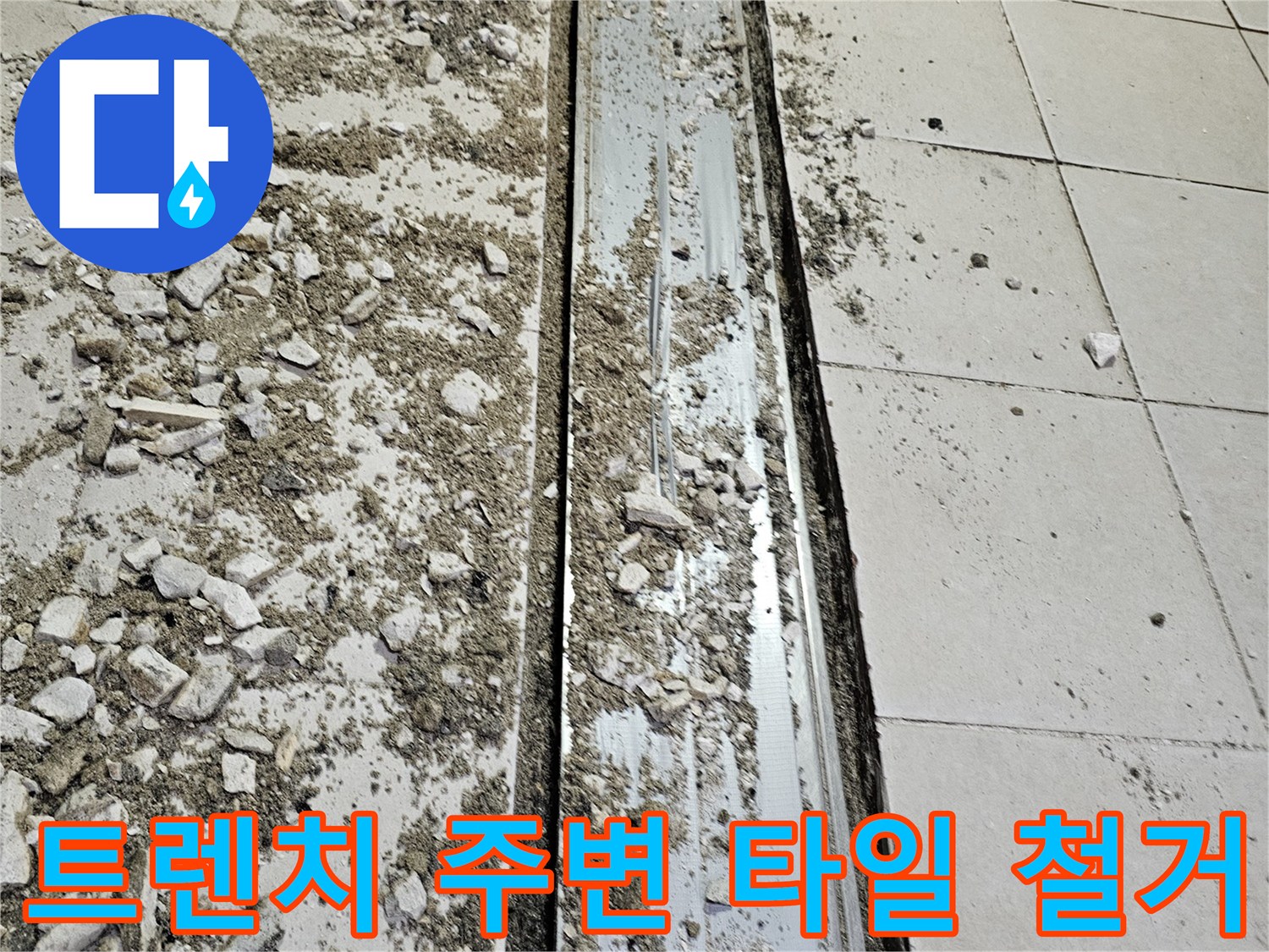 식당 주방의 배수 트렌치 덮개와 주변 타일이 파손되어 철거된 모습입니다.