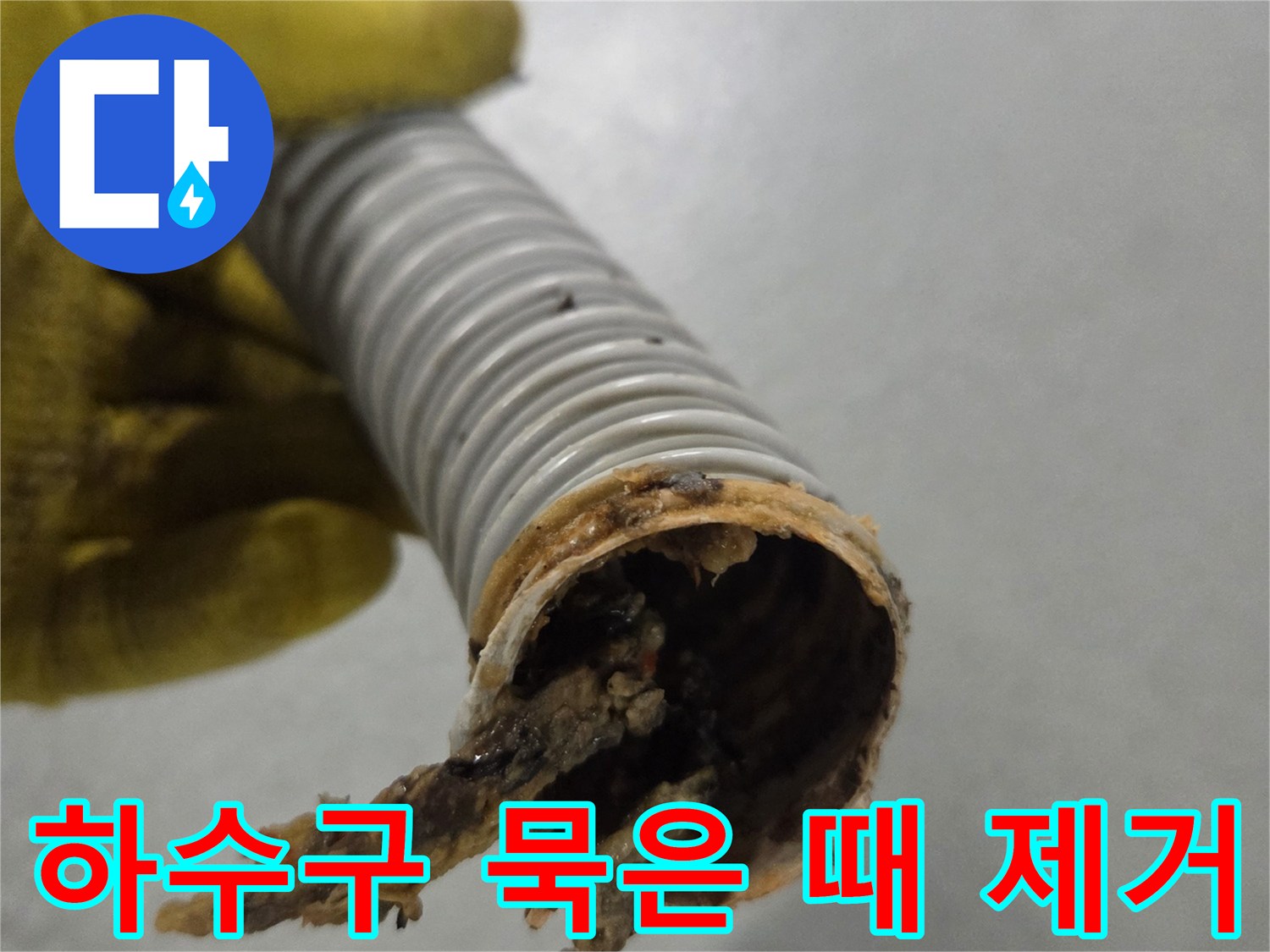 노란색 장갑을 낀 손이-오랜 시간 사용으로 더러워진 배수관을 보여주고 있습니다.