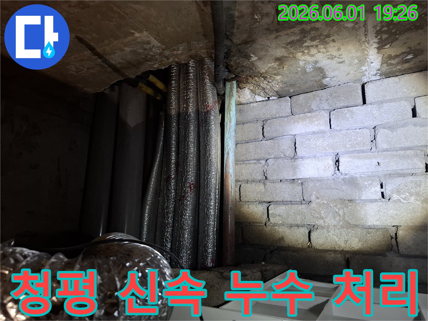 어두운 지하 공간에서-천장 배관과-벽돌 벽면의-누수 흔적을-확인하는 모습의-누수탐지 현장 사진입니다