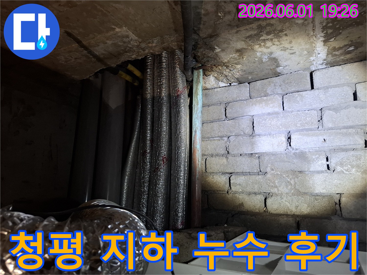 어두운 지하 공간에서-천장 배관과-벽돌 벽면의-누수 흔적을-확인하는 모습의-누수탐지 현장 사진입니다