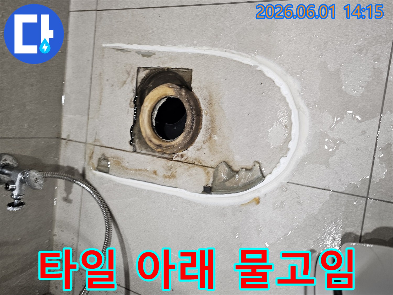 변기를 들어낸 자리에서-타일 아래로 물이 스며들어 고여있는 누수 현장을 보여주는 사진입니다
