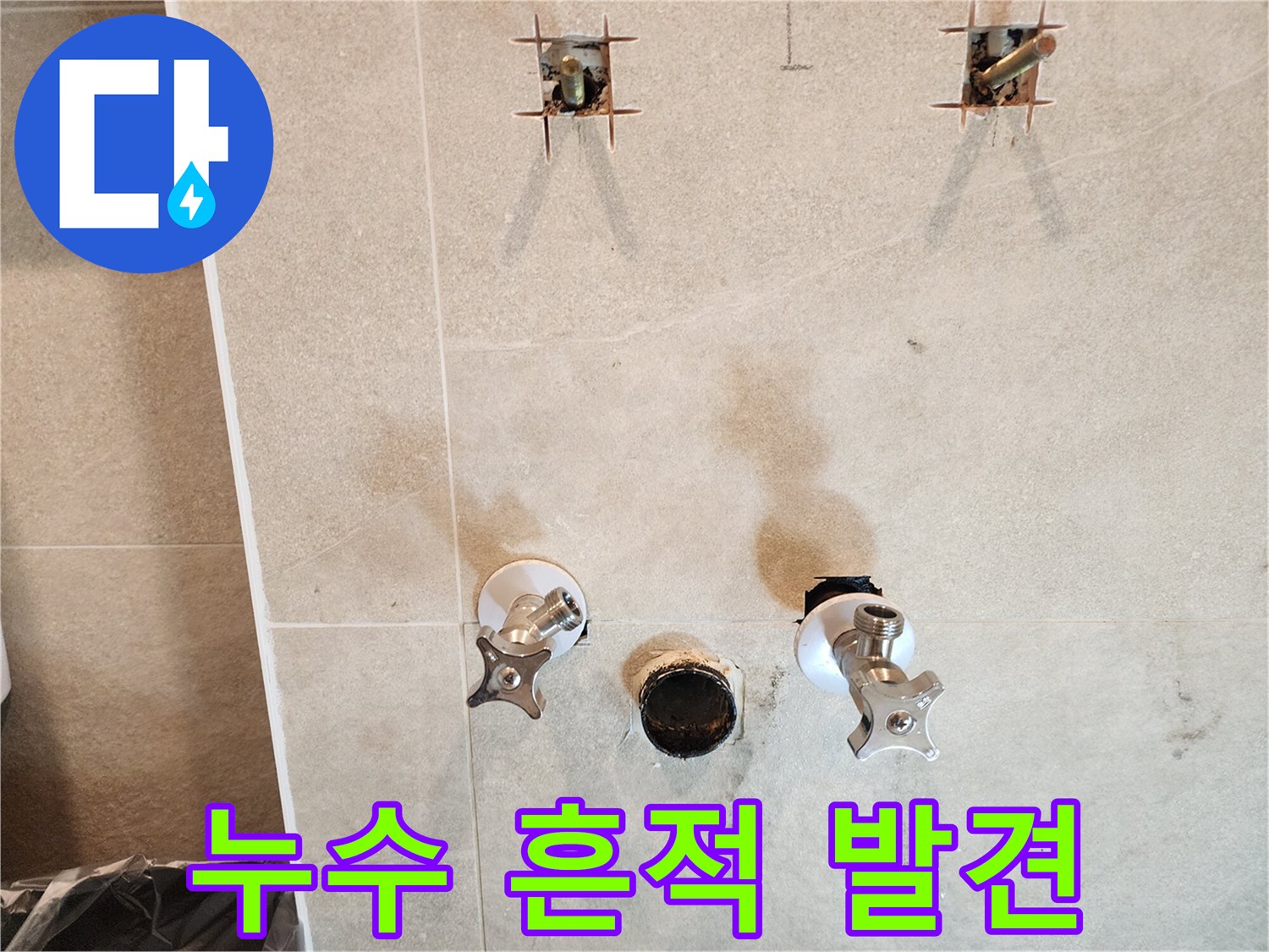 욕실 타일 벽면에 나타난 물샘 자국과 노출된 배관 부속들