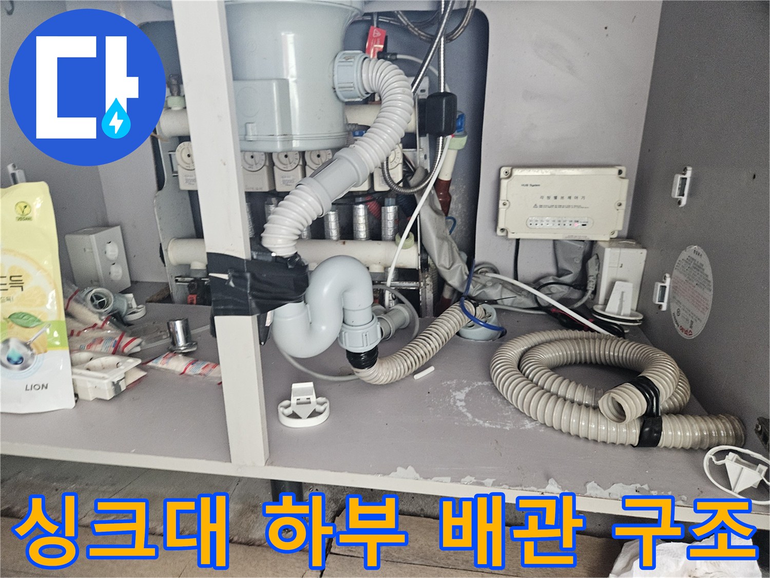 싱크대 밑바닥-배수 호스와 연결 관들의 복잡한 배치 상태입니다.