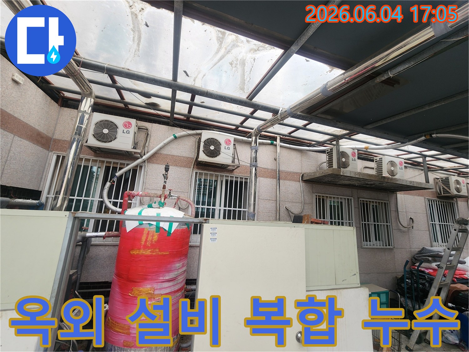 이 이미지는 건물 외부에 설치된-다양한 에어컨 실외기와-물탱크-그리고 복잡한 배관들이 얽혀있는 모습을 보여줍니다