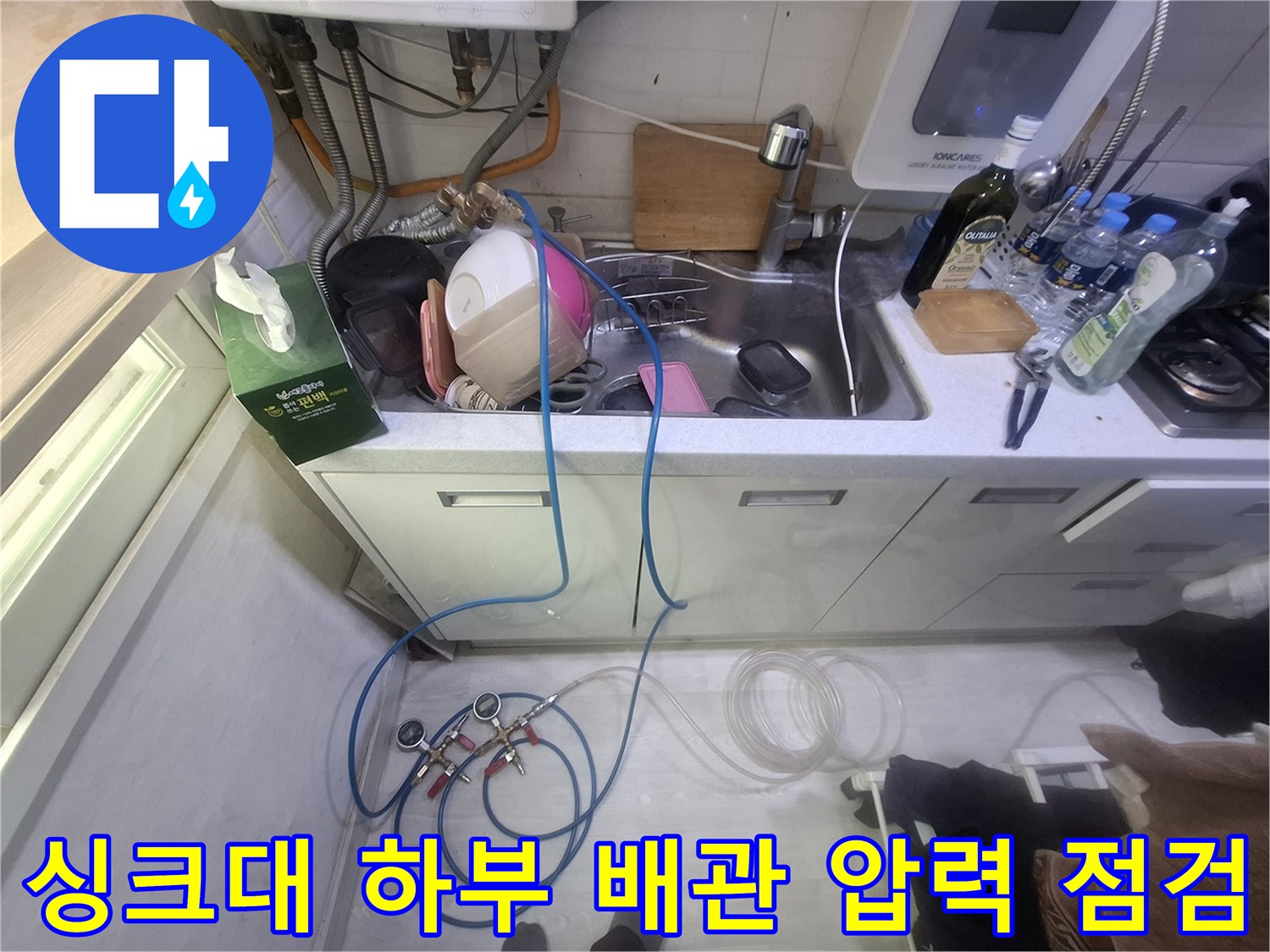 싱크대 아래 수도 밸브와 연결된 파란색 공압 호스 모습