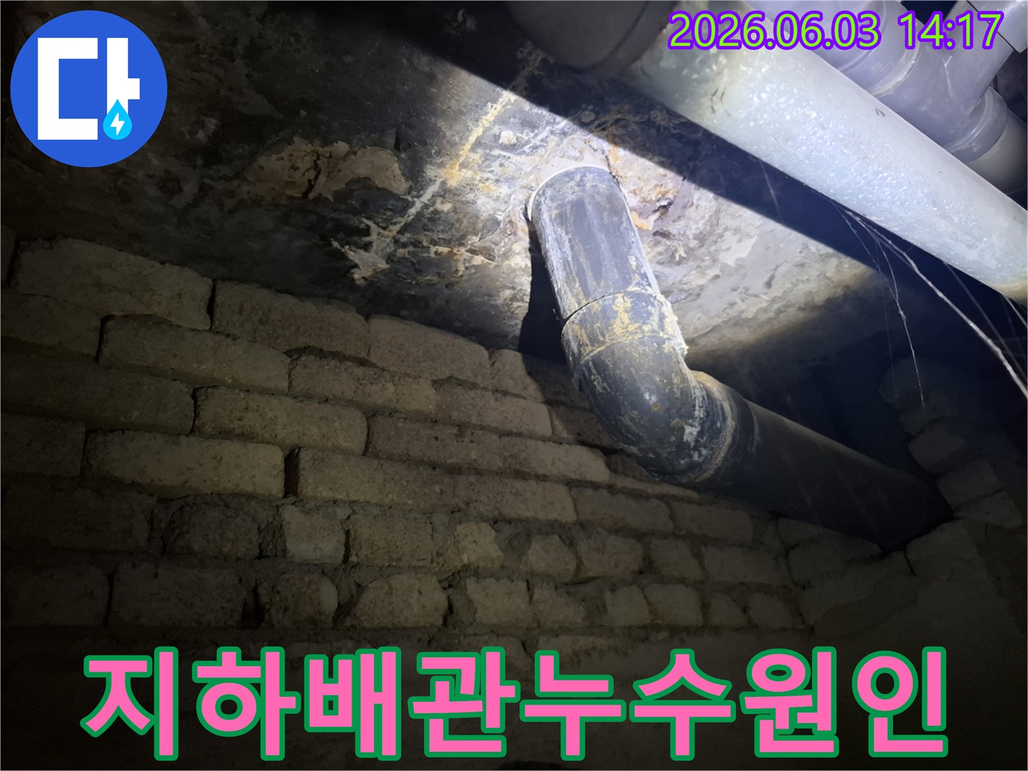 어두운 지하 공간에서-낡은 배관과-벽돌 벽에 발생한-누수 흔적을-조명으로 비춰-정밀하게 검사하는 모습