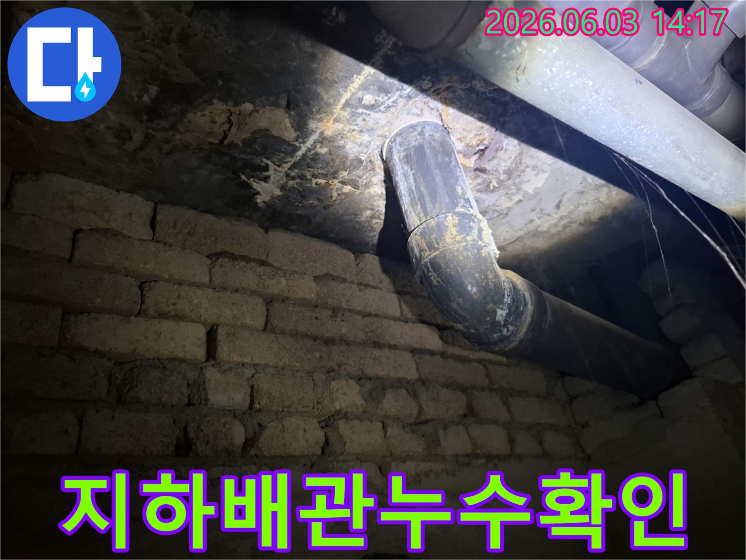 어두운 지하 공간에서-낡은 배관과-벽돌 벽에 발생한-누수 흔적을-조명으로 비춰-정밀하게 검사하는 모습