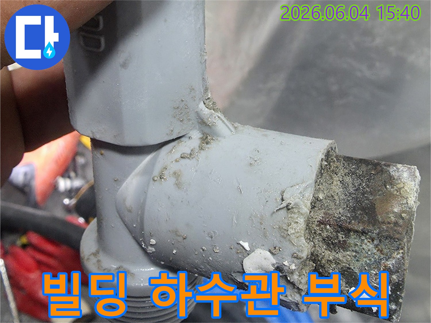 빌딩 하수관에서 발견된 심하게 부식되어 교체가 필요한 상태를 보여주는 이미지-내부의 이물질과 부식으로 인해 배관의 기능이 저하되었습니다