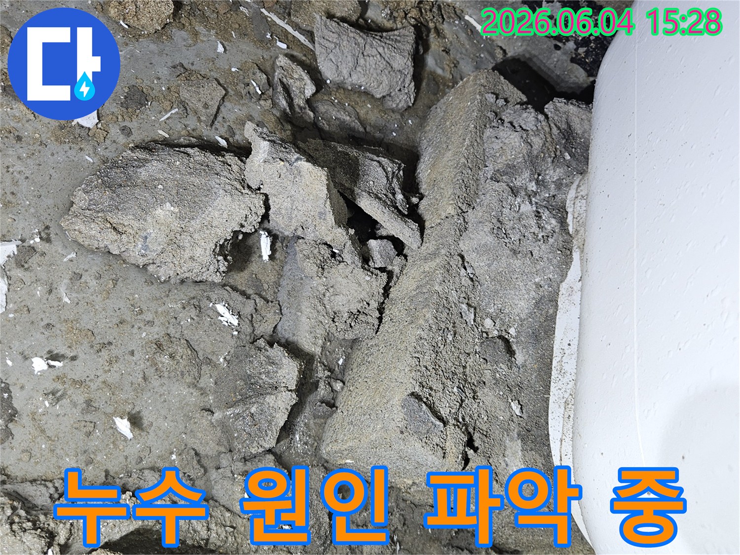 이 이미지는-변기 하부에서 발생한 물샘 현상을-정확히 파악하기 위해-바닥을 조심스럽게 파쇄한-작업 과정을 보여줍니다.