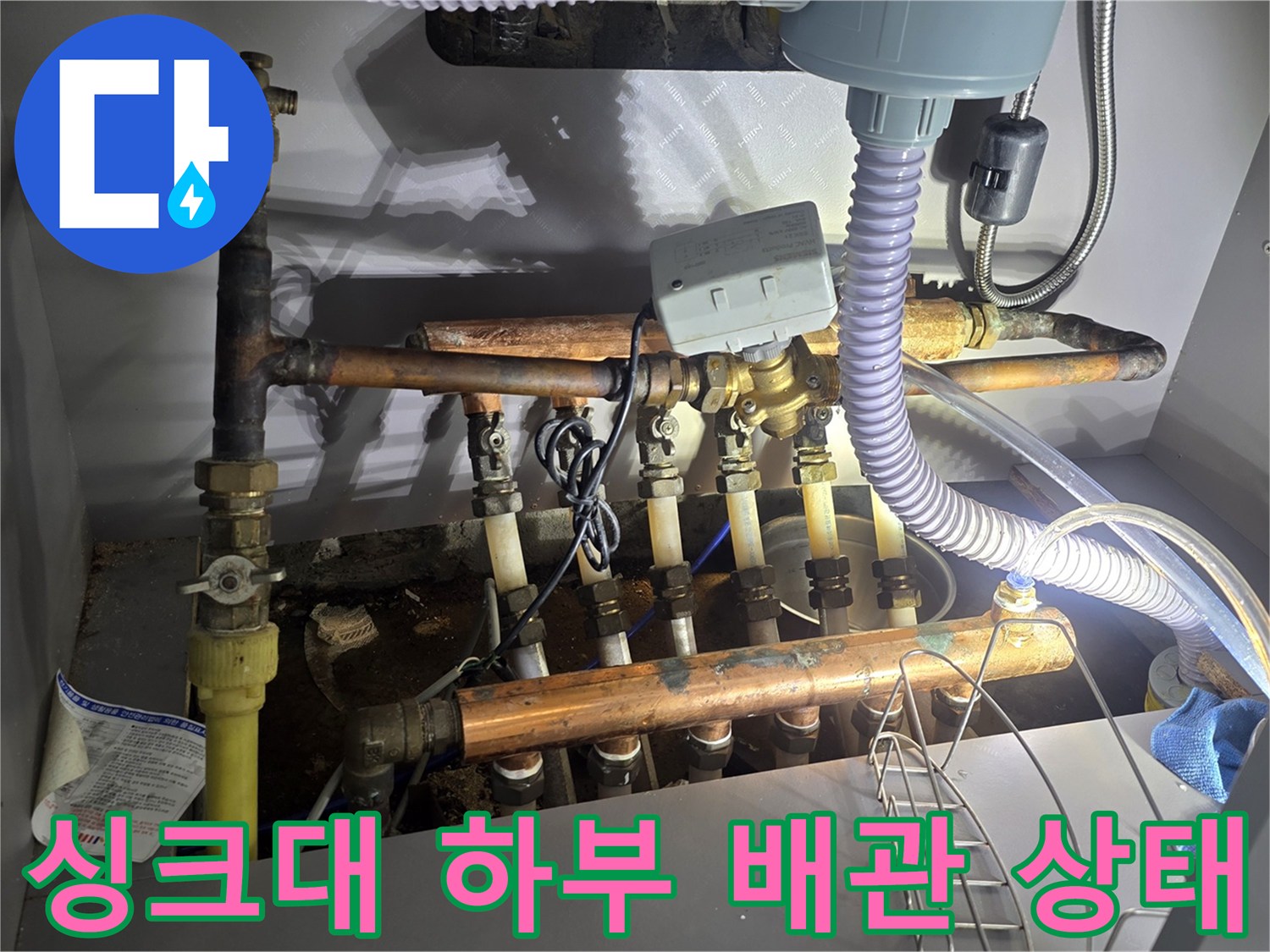 부식과 물기가 관찰되는 싱크대 하단 보일러 분배기 사진입니다.