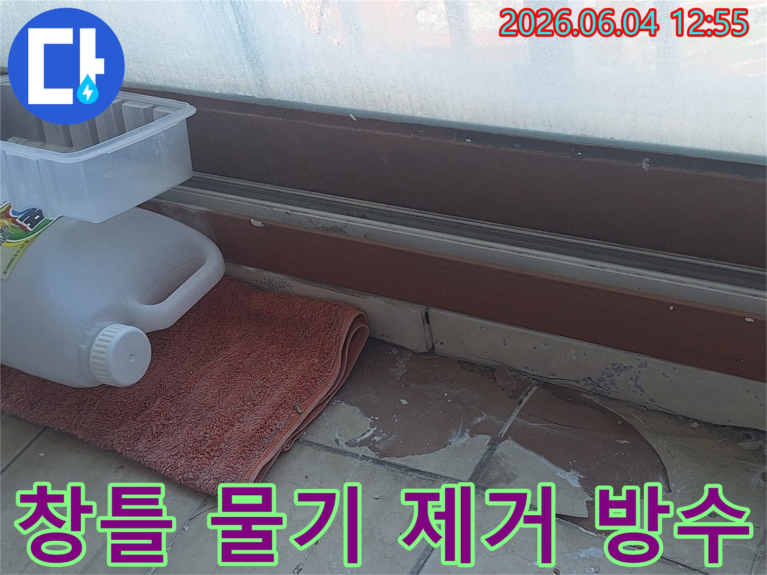 베란다 창틀 주변 바닥의 물기 흔적-손상된 타일과 물기 제거를 위한 수건-누수 원인 파악 후 방수 작업 준비-안전하고 쾌적한 환경 조성을 위한 노력