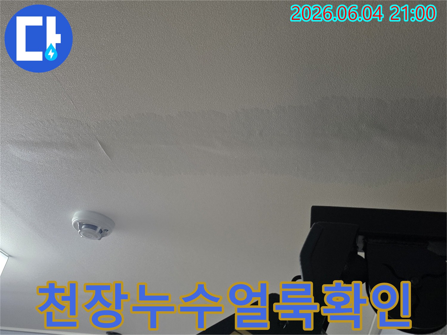 누수로 인해 천장에 생긴-길고 어두운 물 얼룩을 보여주는 사진입니다
